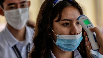 Petugas mengecek suhu siswa yang akan masuk universitas di Manila, Filipina. Alat pengecek suhu genggam menjadi yang paling banyak dipakai untuk deteksi dini virus corona. Foto: Getty Images