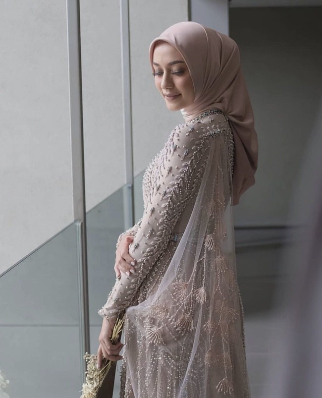 Hijabers asal Bandung ini mengenakan hijab maxmara warna dusty pink yang dililit rapi ke belakang. Mega memakai dress dari perancang busana Renzilazuardi. Foto: Instagram @Renzilazuardi