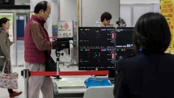 Seorang penumpang dicek terlebih dulu suhu tubuhnya sebelum melakukan penerbangan menuju Wuhan di konter check-in Spring Airlines di bandara Haneda, Tokyo. Foto: Getty Images