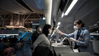 Petugas kesehatan memantau pemindai termal ketika penumpang tiba di bandara Narita, Jepang. Foto: Getty Images