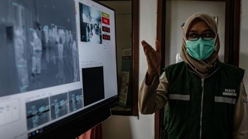 Seorang petugas kesehatan memantau suhu penumpang di Bandara Internasional Adisucipto Yogyakarta, Indonesia lewat monitor pemindai thermal pada saat kedatangan penumpang dari penerbangan internasional. Foto: Getty Images