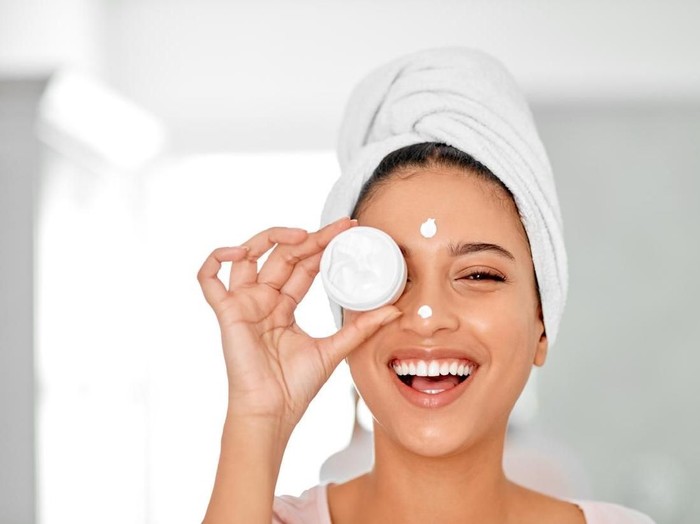 Shot of an attractive young woman covering her eye with a beauty product in her bathroom at home