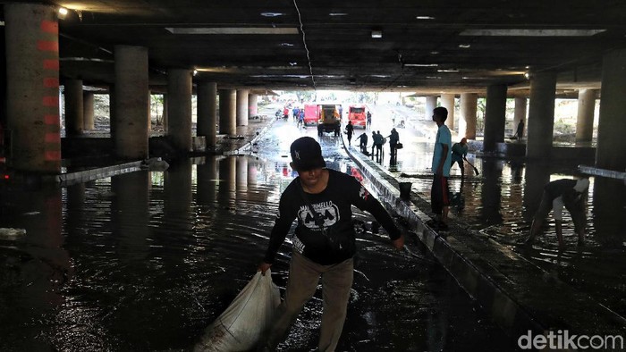 Sejumlah petugas membersihkan sisa lumpur dan air yang masih berada di underpass Kemayoran, Jakarta  Senin (10/2). Menurut keterangan petugas saat ini underpass Kemayoran belum bisa dilalui kendaraan karena masih dalam tahap pengeringan.
