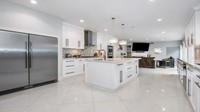 Dapur rumah ini terbuka ke ruang tamu utama dan memiliki meja marmer serta lemari khusus, yang menampung banyak makanan.