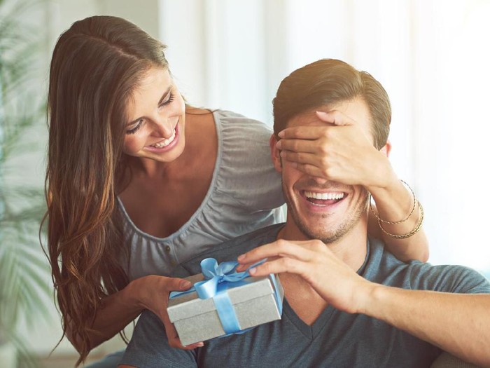 514518036 A young woman covering her husbands eyes for a surprise gift