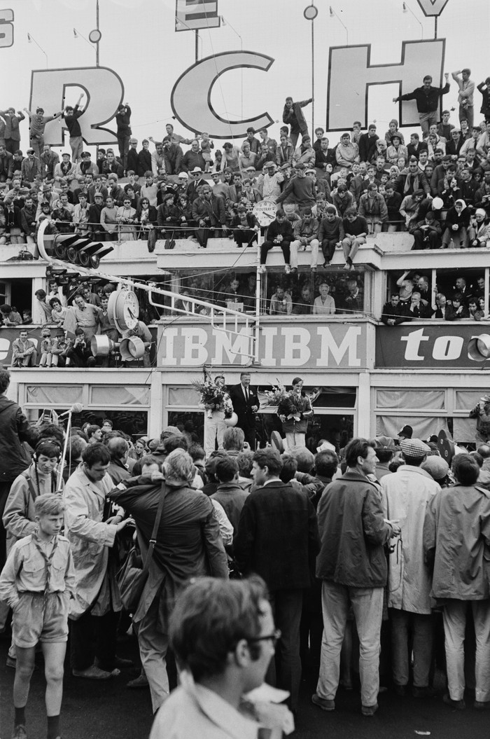 The crowd celebrating New Zealand racing drivers Bruce McLaren (1937 - 1970, left) and Chris Amon (1943 - 2016, right) with Ford CEO Henry Ford II (1917 - 1987, centre) on the podium after winning the 24 Hours of Le Mans, the 34th Grand Prix of Endurance in Le Mans, France, 19th June 1966. (Photo by Reg Lancaster/Daily Express/Hulton Archive/Getty Images)