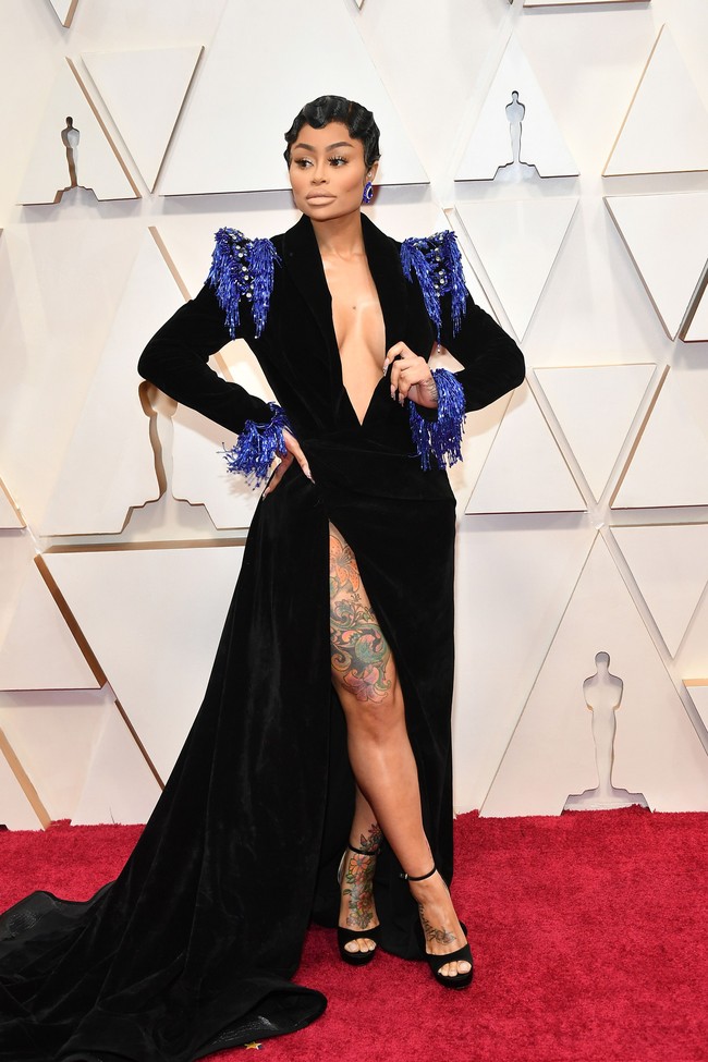 Blac Chyna menebar aura seksinya di Oscar 2020 dengan gaun hitam velvet berbelahan dada rendah yang dihiasi embellishment biru. Gaun tersebut juga hadir dengan belahan rok tinggi yang mengekspos kakinya yang bertato. Penampilan mantan pasangan Rob Kardashian ini membuat mata terbelalak bukan karena alasan yang bagus, tapi penampilannya terlihat terlalu vulgar dan terkesan murahan. Foto: Amy Sussman/Getty Images