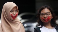 Para peserta aksi melakukan aksi diam. Gambar bekas telapak tangan berwarna merah juga terlihat di mulut mereka.