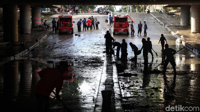 Sejumlah petugas membersihkan sisa lumpur dan air yang masih berada di underpass Kemayoran, Jakarta  Senin (10/2). Menurut keterangan petugas saat ini underpass Kemayoran belum bisa dilalui kendaraan karena masih dalam tahap pengeringan.