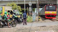 Pengendara menghentikan kendaraannya saat kereta melintas di perlintasan Rawa Buaya.