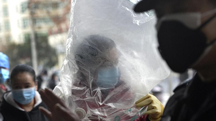 Seorang pria di Hubei, China, terlihat menggunakan penutup kepala menggunakan plastik saat beraktivitas. Hal itu dilakukan demi mencegah penularan infeksi corona.