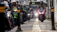 Seorang pengguna motor tampak percaya diri dengan gagah berani melintasi jalur pejalan kaki.