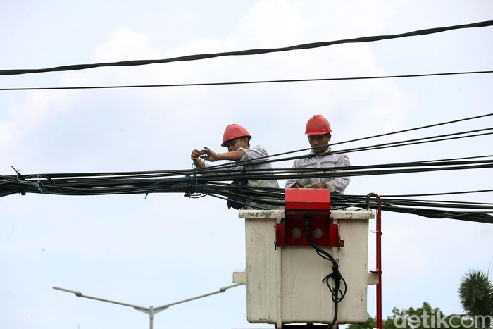 Dua petugas dari Suku Dinas (Sudin) Perindustrian dan Energi Jakarta Pusat, tengah membenahi dan merapikan kabel yang semrawut di Jalan HOS Cokroaminoto, Kuningan, Jakarta, Selasa (11/2/2020).