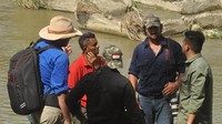 Warga negara Australia, Matthew Nicolas Wright (kedua kanan) dan Chris Wilson (kiri) berbincang dengan petugas saat memantau lokasi kemunculan seekor buaya liar yang terjerat ban sepeda motor di Sungai Palu di Palu, Sulawesi Tengah, Selasa (11/2/2020).