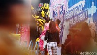 Seorang anak bersalaman dengan cosplayer Transformer.