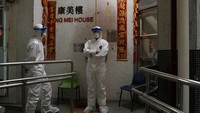Sejumlah petugas mengenakan masker dan pakaian pelindung bersiaga di depan apartemen yang berada di pinggiran Kota Hong Kong, Selasa (11/2/2020).
