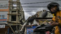 Pengendara motor melintas di samping bangunan yang ambruk di Jalan Pisangan Baru, Matraman, Jakarta, Selasa (11/02/2020).