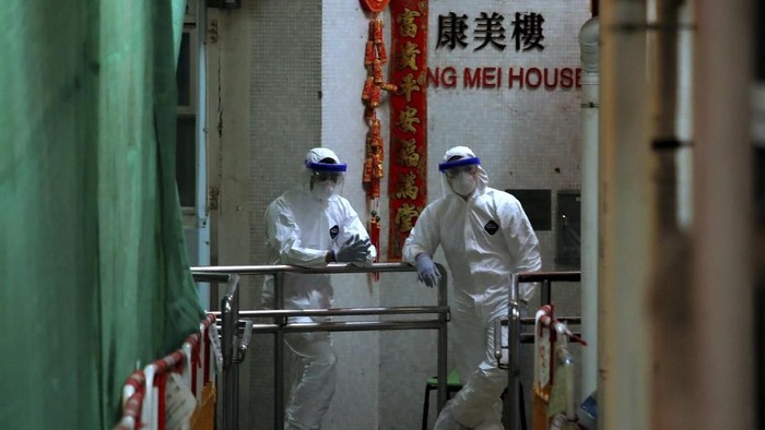Personnels wearing protective suits wait near an entrance at the Cheung Hong Estate, a public housing estate during evacuation of residents in Hong Kong, Tuesday, Feb. 11, 2020. The Centre for Health Protection of the Department of Health evacuated some residents from the public housing estate after two cases of novel coronavirus infection to stop the potential risk of further spread of the virus. (AP Photo/Kin Cheung)