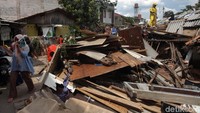 Seorang warga tampak sedang melintas di samping puing-puing bangunan kosan yang sedang dibersihkan oleh petugas gabungan.