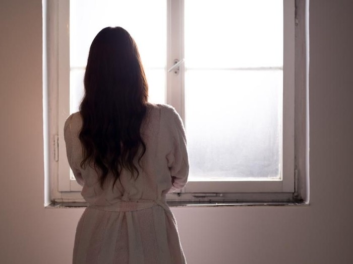 Woman suffering from cancer looking through hospital window.