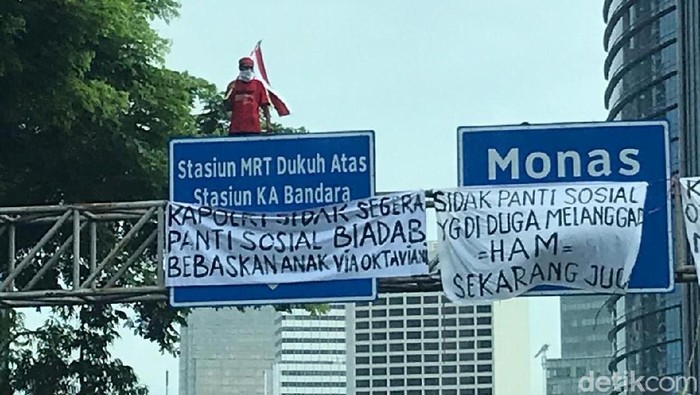seorang pria panjat tiang rambu di jalan mh thamrin