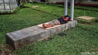 Seorang warga beristirahat dengan tiduran di taman rusunawa.
