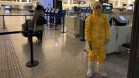 Tak hanya masyarakat yang mengenakan masker, petugas bandara pun mengenakan seragam yang jauh lebih kompleks (Edward Wang/Reuters)