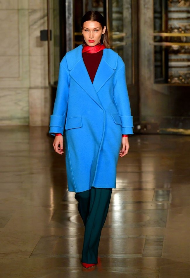 Bella Hadid ikut memeriahkan fashion show desainer Oscar De La Renta di New York Fashion Week, 10 Februari 2020. Model 23 tahun itu tampil tertutup saat melenggang di catwalk. Dia mengenakan coat biru yang dipadukan dengan celana panjang hijau dan atasan merah serta scarf. Foto: Frazer Harrison/Getty Images