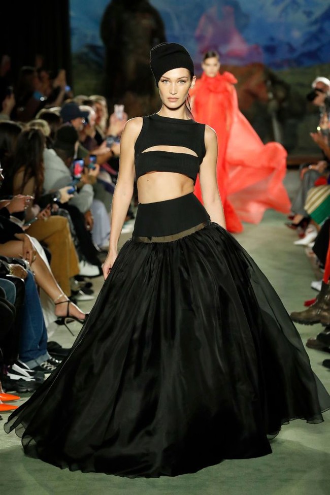 Bella Hadid kemudian kembali melenggang di catwalk fashion show Brandon Maxwell tetap dengan busana yang mengekspos perut ratanya. Kali ini Bella tampil serba hitam dengan rok lebar dan atasan crop top. Foto: Frazer Harrison/Getty Images