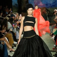 Bella Hadid kemudian kembali melenggang di catwalk fashion show Brandon Maxwell tetap dengan busana yang mengekspos perut ratanya. Kali ini Bella tampil serba hitam dengan rok lebar dan atasan crop top. Foto: Frazer Harrison/Getty Images