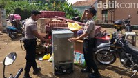 Polisi membantu mengevakuasi barang-barang milik korban longsor.