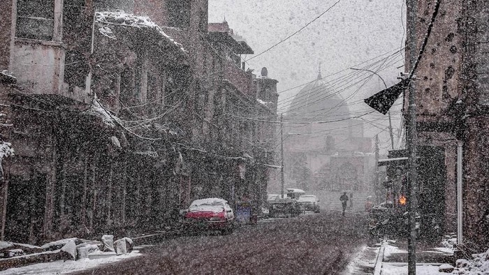 This picture taken on February 10, 2020 amidst a heavy snow storm shows a view along Sarjkhana street in the old town of Iraq's northern city Mosul with the background showing the dome of the Nuri mosque, which was heavily damaged by Islamic State (IS) group fighters in the 2017 battle for the city. (Photo by Zaid AL-OBEIDI / AFP)