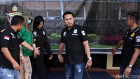 Lucinta dihadirkan dengan memakai baju tahanan, masker dan topi.
