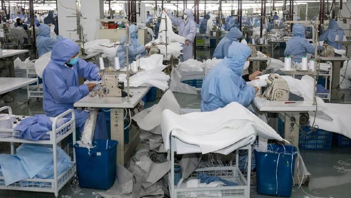 (FILES) This file photo taken on February 8, 2020 shows workers producing protective clothing at a factory which previously produced suits and sportswear and switched production for the fight against the deadly COVID-19 coronavirus, in Wuxi in Chinas eastern Jiangsu province. - A diaper manufacturer in eastern China was closed for the Lunar New Year holiday when it heard from officials that China needed vast amounts of masks to fight the virus epidemic and factories needed to chip in, and in just over two days converted a manufacturing line in Fujian province to make face masks. (Photo by STR / AFP) / China OUT / TO GO WITH China-health-virus-manufacturing,FOCUS by Beiyi SEOW