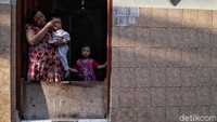 Seorang warga tengah menyuapi bayinya di depan pintu rumahnya. Hingga kini, korban virus corona sudah tembus diangka 1300 orang dalam waktu yang tidak cukup lama.