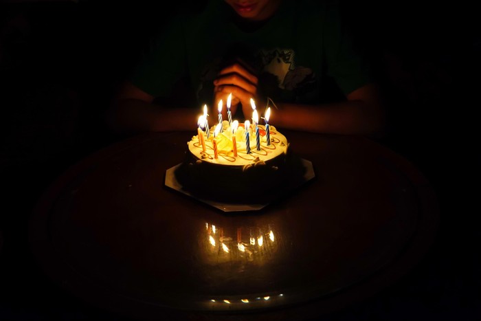 The boy is requesting blessings on his birthday by having a cake.