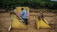 Seorang warga beraktifitas diantara puing-puing bangunan rusak pasca diterjang banjir bandang di Desa Pajagan, Lebak, Banten, Kamis (13/2/2020).