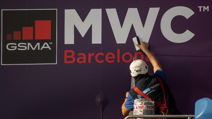 MWC A worker fixes a poster announcing the Mobile World Congress 2020 in a conference venue in Barcelona, Spain, Tuesday, Feb. 11, 2020. Intel Mobile is the latest company announcing that is pulling out of the Mobile World Congress scheduled to be held in Barcelona in late February. Authorities still seem to be committed to hold it, meeting foreign diplomats on Tuesday to brief on the efforts to prevent any spread of the new coronavirus virus during the industry show. (AP Photo/Emilio Morenatti)