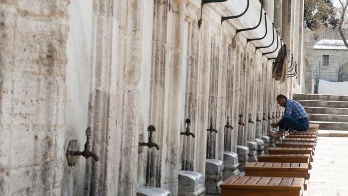 Istanbul, Turkey - April 07, 2012: Man performing ablution. Ablution is a ritual act, where the person washes himself/herself in order to get ready for the prayer. Image taken during midday at the fountains next to Sultanahmet Mosque in Istanbul.