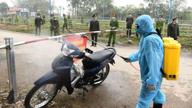 Petugas menyemprot kendaraan yang melintas di pos pemeriksaan di wilayah Son Loi dengan disinfektan