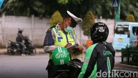 Polisi memberikan surat tilang kepada pengendara sepeda motor yang melanggar lalu lintas.