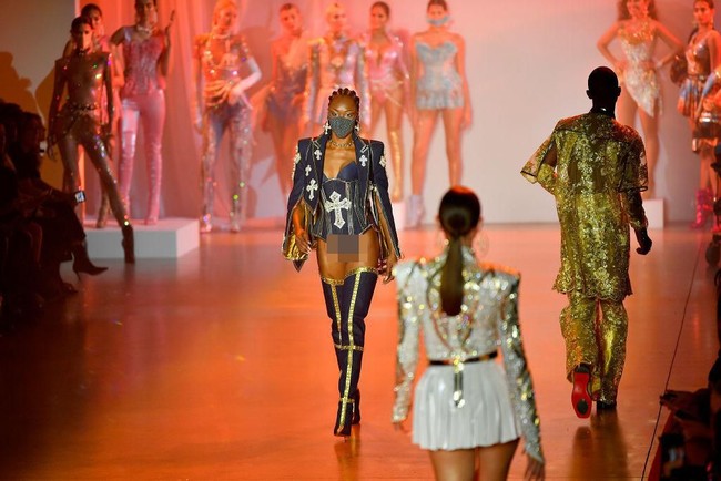 Model tampil seksi memakai jaket dan leotard yang dipadukan dengan masker berkilauan yang dihiasi bebatuan. Masker glamour ini hadir di fashion show The Blonds, New York Fashion Week 2020. Foto: Getty Images