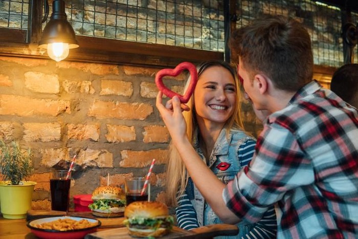 Young couple in a restaurant, drinking wine. Both about 25 years old, Caucasian.