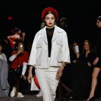 Mengenakan rok dan jaket putih gading serta topi beret, Gigi Hadid tampil ala wanita era 60-an yang memang menjadi inspirasi koleksi terbaru Marc Jacobs. Foto: Getty Images