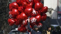 Seorang pedagang menjajakan balon bertuliskan Happy Valentines Day di kawasan Kabul, Afghanistan. AP Photo/Rahmat Gul.