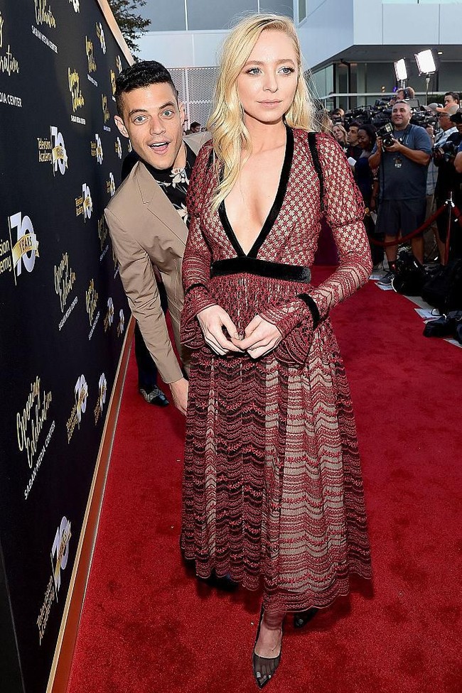 Muka Rami Malek yang nongol di belakang Portia Doubleday saat dia pose di red carpet adalah salah satu momen terlucu yang pernah tertangkap kamera fotografer.Foto: Getty Images