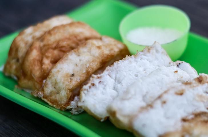 Kue pancong atau kue bolu dan gula dengan latar belakang kayu.  Makanan jalanan di Jakarta, Indonesia.