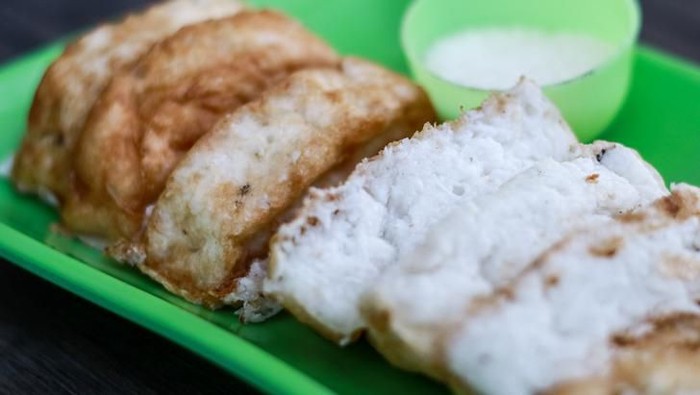 Pancong cake or kue pancong and sugar on wood background. Street food in Jakarta, Indonesia.