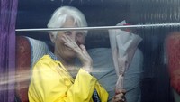 Seorang penumpang kapal melambaikan tangan dan tersenyum setelah naik ke dalam bus untuk melanjutkan perjalanan kembali ke rumah usai diizinkan berlabuh dan turun dari kapal pesiar Westerdam di Kamboja.
