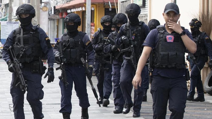 Police in tactical gear leave the site of a shooting in Bangkok, Thailand, Friday, Feb. 14, 2020. Multiple gunshots were fired in the air by a man in the middle of the capital Bangkok, police said Friday. The man suspected of firing some 20-40 shots was refusing to surrender more than six hours later. (AP Photo/Sakchai Lalit)